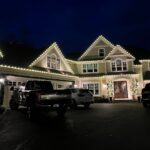 Professional holiday light installation on a Massachusetts home with custom warm white roofline lighting.